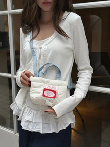 Dettaglio borsa a tracolla trapuntata bianca con cinturino in denim blu e logo ciliegia
