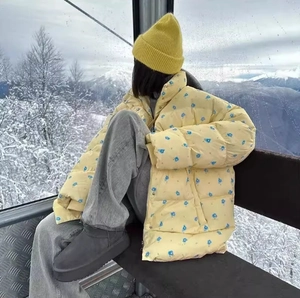 Detail of yellow floral winter puffer jacket with blue flower print and stand collar