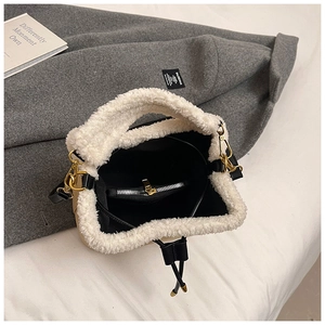 Detail view of khaki suede bucket bag with white faux fur trim and gold metal zipper