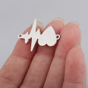 Macro detail of heartbeat and heart stainless steel charm connector held by fingers
