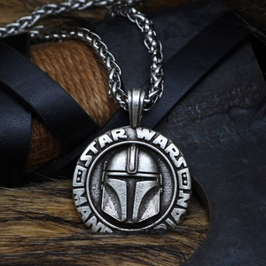 Detailed macro of silver Mandalorian helmet pendant on a rugged chain with fur background