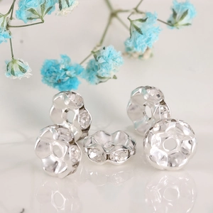 Macro shot of silver petal-shaped spacer beads with clear rhinestones for jewelry DIY