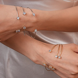 Détail de bracelets ouverts dorés et argentés avec des zircons en forme d'étoile et goutte