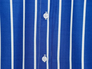 Détails macro des boutons en résine blanche sur une chemise rayée bleue et blanche