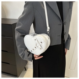 Sac à bandoulière blanc en forme de cœur avec rivets et boucle sur un blazer gris