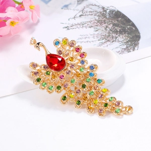 Vintage peacock brooch with colorful rhinestones and red teardrop crystal on white backdrop