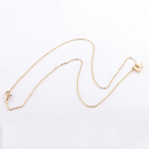 Collier minimaliste en acier inoxydable doré avec un pendentif lettre U minuscule sur fond blanc