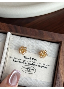 Macro shot of flower pearl stud earrings with crystal accents on a wooden jewelry display