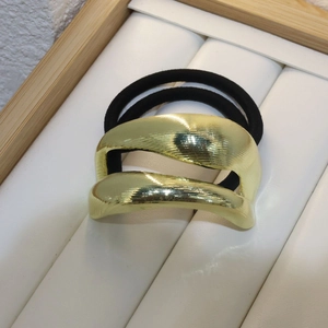 Minimalist golden metal hair tie with brushed texture and black elastic band for women