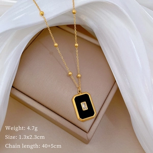 Detail of gold necklace with black enamel pendant and zircon resting on jewelry box