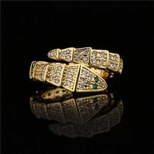 Vintage gold snake ring featuring white zircon pave and green stone eyes with wrap design