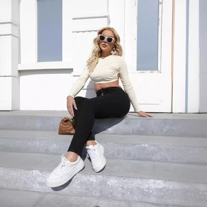 Women's slim fit high waist denim jeans paired with beige crop top in outdoor setting