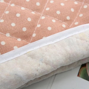 Detailed macro view of quilted brown fabric with white dots and thick heat-resistant lining