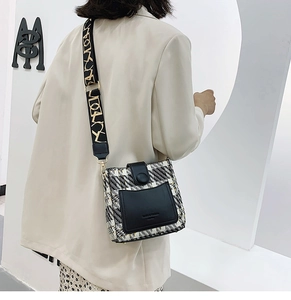 Detail of tweed and leather crossbody bag with wide patterned strap on beige blazer