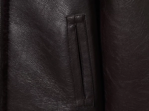 Gros plan des coutures de poche et texture cuir premium sur la veste réversible