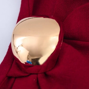 Close-up of burgundy knit fabric with decorative gold metal buckle detailing