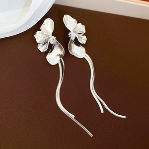 Détail de boucles d'oreilles fleurs en argent avec longues franges sur fond sombre