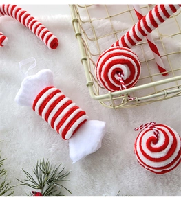 Detail of plush red and white candy cane ornaments on a soft white faux fur background