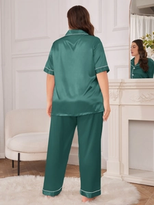 Detail of dark green satin pajama set with contrast white piping and silk finish