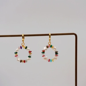 Colorful checkered natural stone circle earrings with gold hooks on a metal display stand