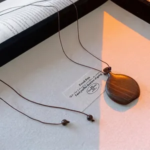 Vintage dark brown wood teardrop pendant necklace with natural grain on white canvas
