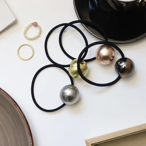 Close-up of four metallic spherical elastic hair ties in gold and silver finish