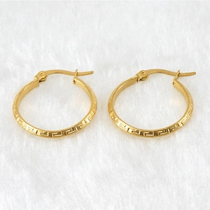 Macro shot of 18K gold plated hoop earrings with Greek key engraving on white fur