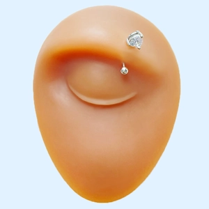 Detail view of silver curved eyebrow ring with clear heart-shaped zircon on a model