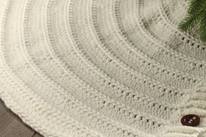 Close-up of cream chunky knit Christmas tree skirt with dark brown wooden buttons