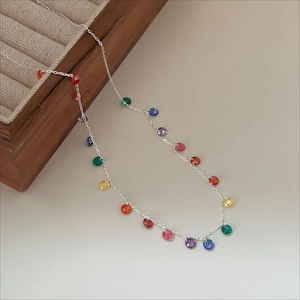 Detail of multi-color faceted beads on a silver chain displayed on a wooden jewelry box