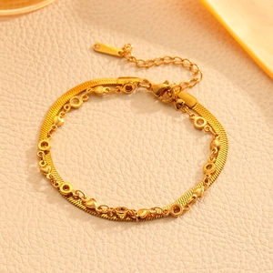 Gros plan d'un bracelet double couche en acier doré avec breloques cœur sur cuir beige