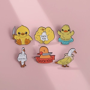 Detailed close-up of creative yellow duck enamel pins set on a soft pink background