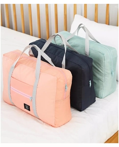 Three colorful waterproof nylon travel bags shown on white bedding for clothing storage