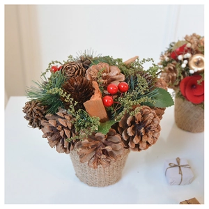 Close-up of a Christmas pine cone potted plant with red berries and burlap wrap