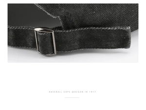 Close-up of the adjustable strap and metal buckle on the black cotton baseball cap