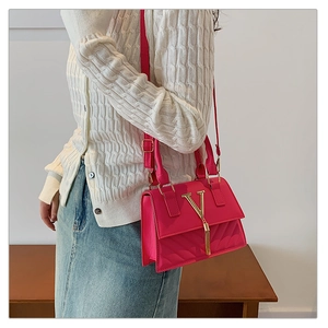 Detail of fuchsia leather handbag with V-quilting and gold tassel showing on model