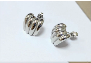 Macro shot of silver ribbed huggie earrings with polished stainless steel finish
