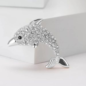 Close-up of dolphin brooch with clear rhinestones and black eye on silver alloy base