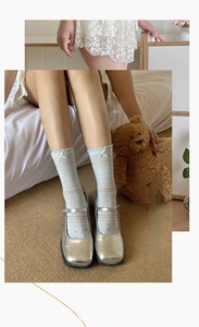 Detail of light blue mesh socks with heart patterns, lace trim and bow accent
