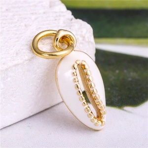 Macro shot of shell-shaped pendant in white enamel with gold metal edges and hanging loop