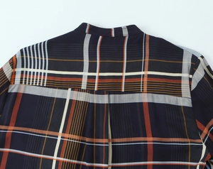 Detail eines blauen Karohemdes mit präzisen Nähten und orangefarbenem Karomuster