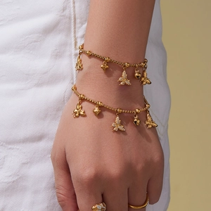 Gouden gelaagde armbandset met vlinder- en hartbedels en fonkelende strass-accenten