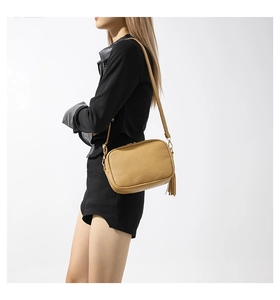 Detail of yellow crossbody bag with lychee texture and stylish leather tassel charm