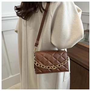 Close-up of brown quilted leather crossbody bag with decorative gold chain and strap