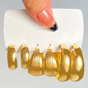Detailed macro view of three pairs of gold-plated geometric hoop earrings set on a card
