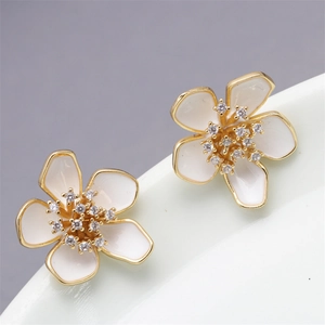Detailed view of copper flower earrings with white enamel petals and diamond centers