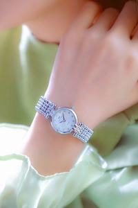 Close-up of a silver quartz watch for women with a white crystal-set dial on a wrist