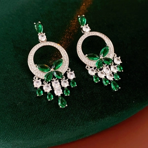 Gros plan détaillé de boucles d'oreilles émeraude et argent avec pompons en cristal