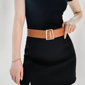 Close-up of a wide brown leather belt with a gold rectangular buckle on a black dress