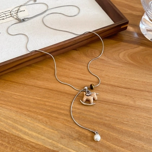 Detail view of silver snake chain necklace with wooden rocking horse pendant and pearls